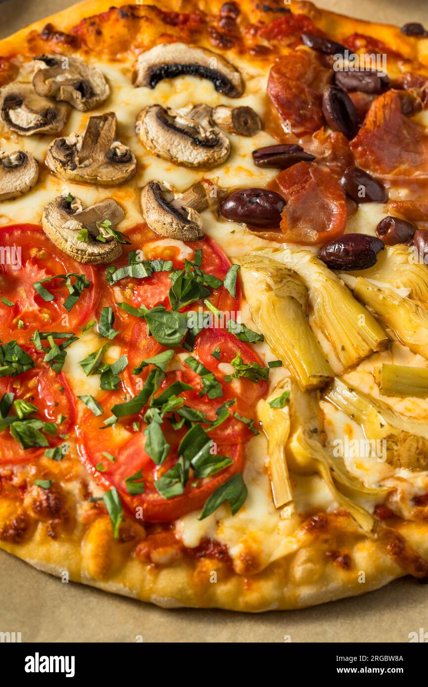 Pizza italiana Four Seasons con pomodoro olive funghi e carciofi Foto Stock