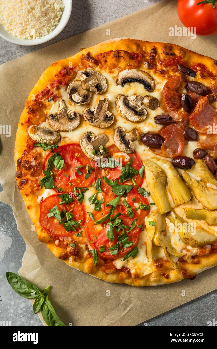 Pizza italiana Four Seasons con pomodoro olive funghi e carciofi Foto Stock
