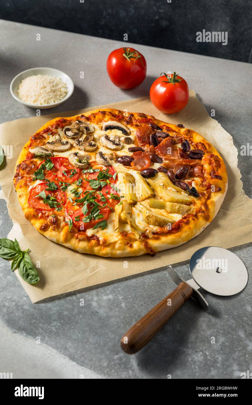 Pizza italiana Four Seasons con pomodoro olive funghi e carciofi Foto Stock