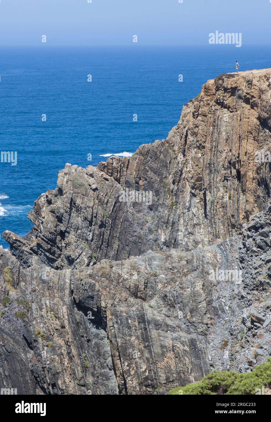 Visitatore che osserva il mare dalla cima della scogliera della costa di Cabo Sardao, Ponta do Cavaleiro, Sao Teotonio, Portogallo Foto Stock