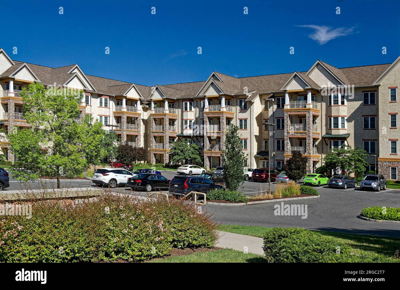 Moderno edificio ad appartamenti a 4 piani, a forma di U, in pietra, stucco, balconi, automobili parcheggiate, giardini, bella giornata di sole, Pennsylvania, estate Foto Stock