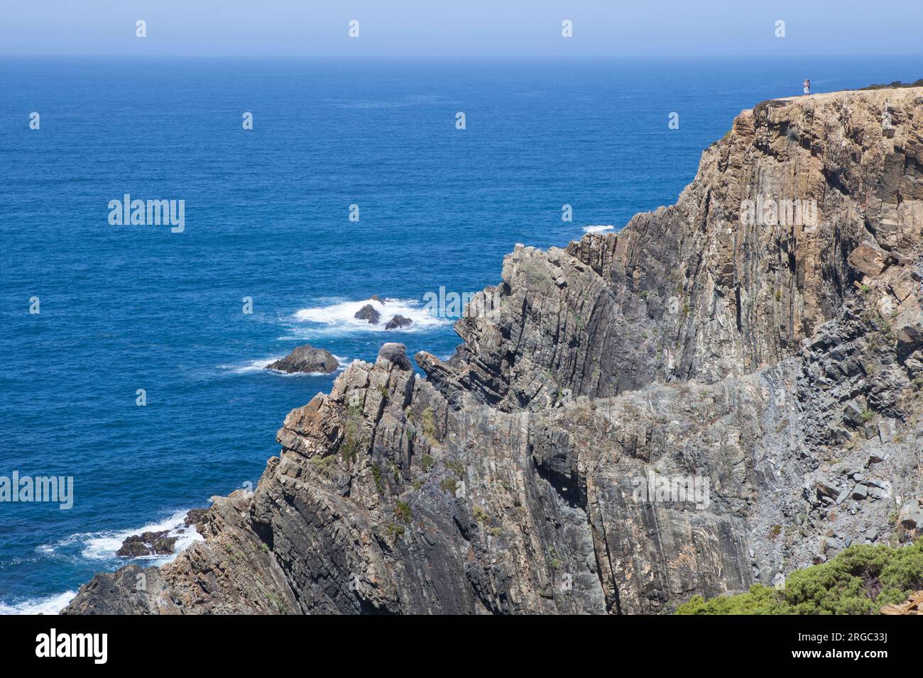 I visitatori osservano il mare dalla cima della scogliera della costa di Cabo Sardao, Ponta do Cavaleiro, Sao Teotonio, Portogallo Foto Stock