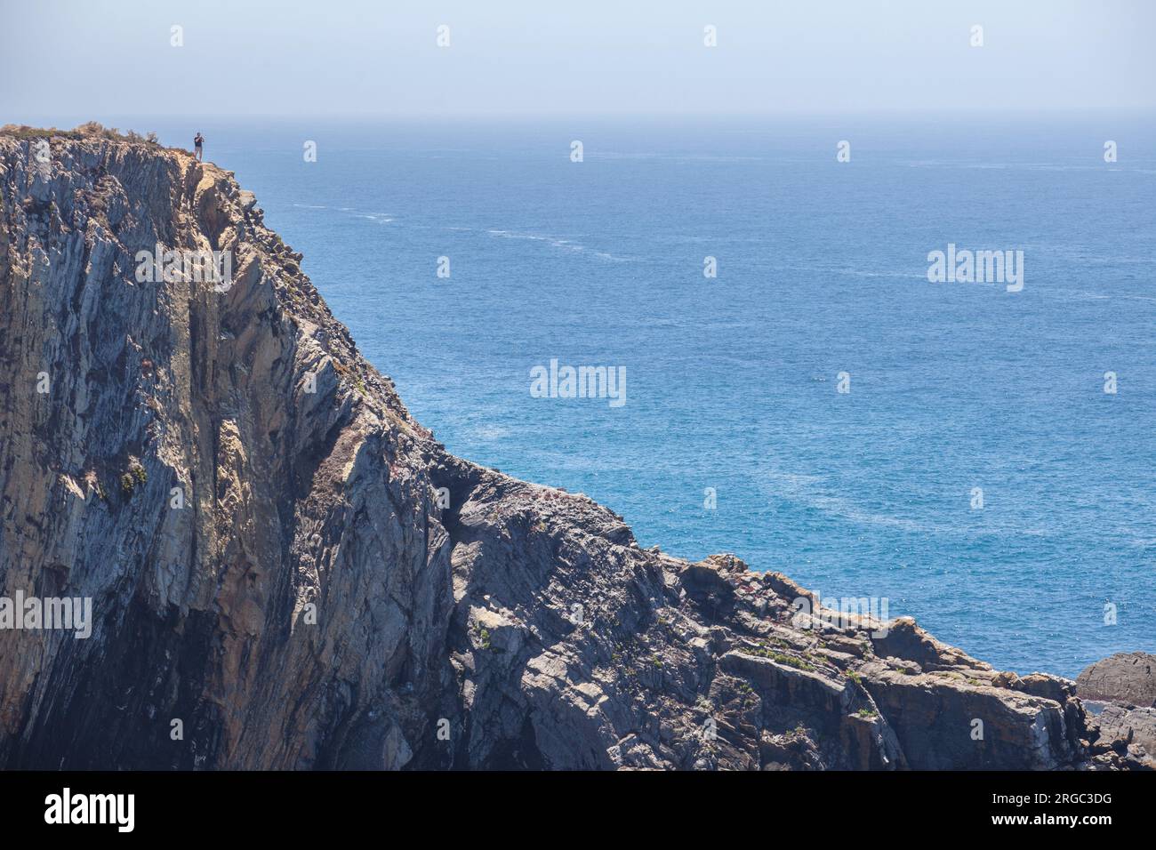 Visitatore che osserva il mare dalla cima della scogliera della costa di Cabo Sardao, Ponta do Cavaleiro, Sao Teotonio, Portogallo Foto Stock