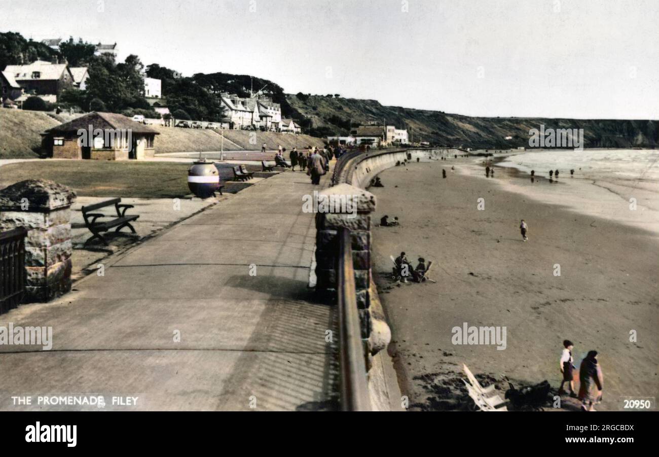 Vista lungo la Promenade a Filey, North Yorkshire, con un paio di persone sulla spiaggia. Foto Stock