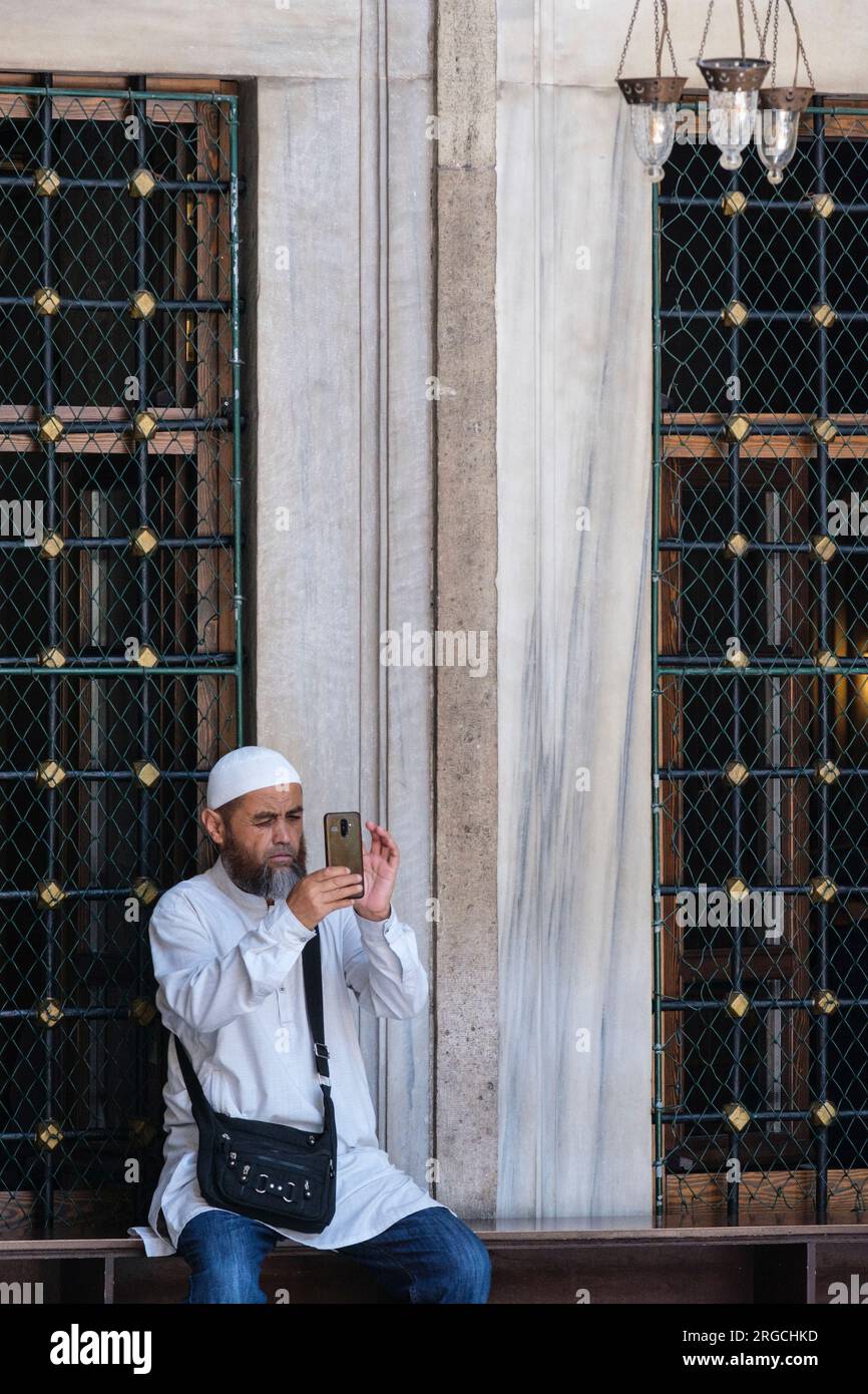 Istanbul, Turchia, Turkiye. Moschea del Sultano Eyup, uomo che scatta foto con il suo cellulare. Foto Stock