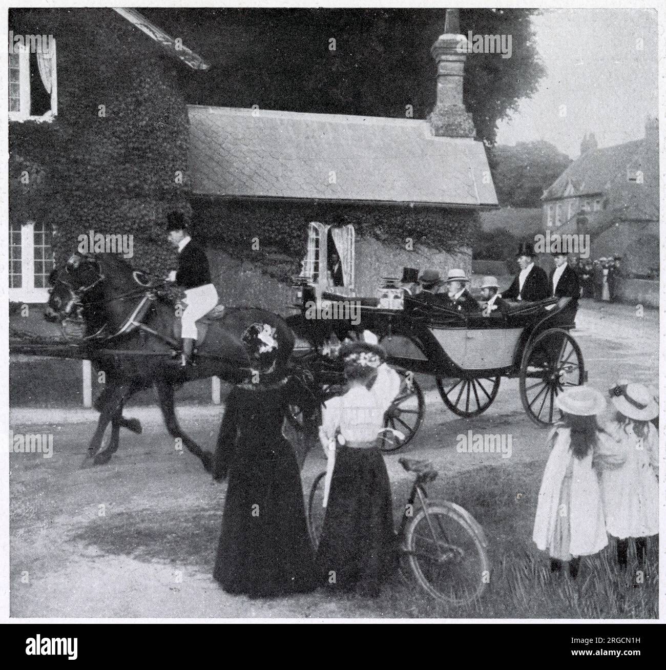 Re Edoardo VII insieme a suo figlio, il Principe di Galles (Giorgio V), guidando attraverso un pittoresco villaggio sulla strada per le corse di Goodwood nel 1906. Foto Stock