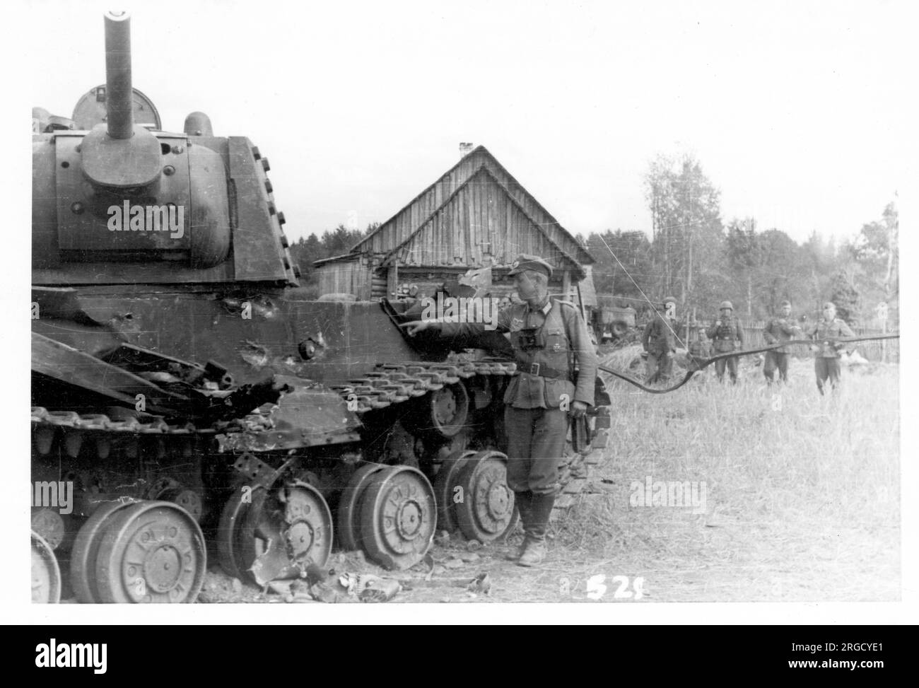 Un carro armato pesante sovietico 'KV-1 Shielded', abbattuto dal fuoco anticarro tedesco, con danni indicati da un soldato tedesco che invade. La 'KV-1 Shielded' era una KV-1 standard con armatura aggiuntiva rivettata sulla torretta e parti dello scafo. La corazza supplementare è visibile sul lato della torretta. (I carri armati di Kliment Voroshilov (KV) sono una serie di carri armati pesanti sovietici che prendono il nome dal commissario per la difesa sovietica e dal politico Kliment Voroshilov) Foto Stock