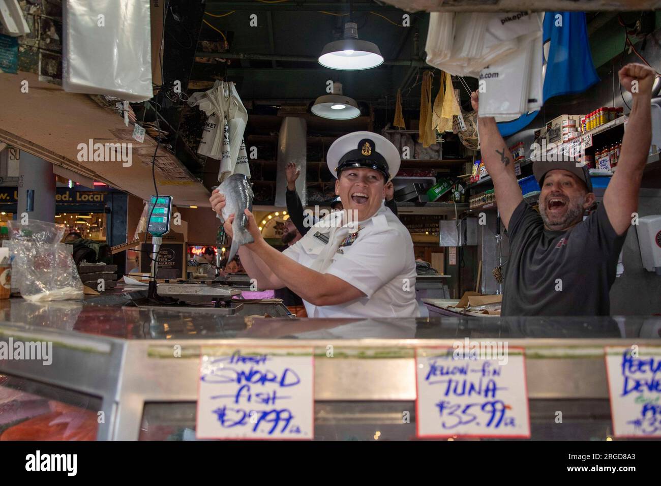 Seattle, Washington, USA. 2 agosto 2023. Il Chief Mass Communication Specialist Gretchen Albrecht, di Chino Hills, California, cattura il pesce con i marinai al Pike Place Market durante la Seattle Fleet Week, 2 agosto 2023. La Seattle Fleet Week è una celebrazione storica dei servizi marittimi e offre ai cittadini di Washington l'opportunità di incontrare marinai, marines e guardiani della costa, nonché di assistere in prima persona alle ultime capacità dei todayâs servizi marittimi statunitensi e canadesi. (Foto di Madison Cassidy) credito: U.S. Navy/ZUMA Press Wire/ZUMAPRESS.com/Alamy Live News Foto Stock