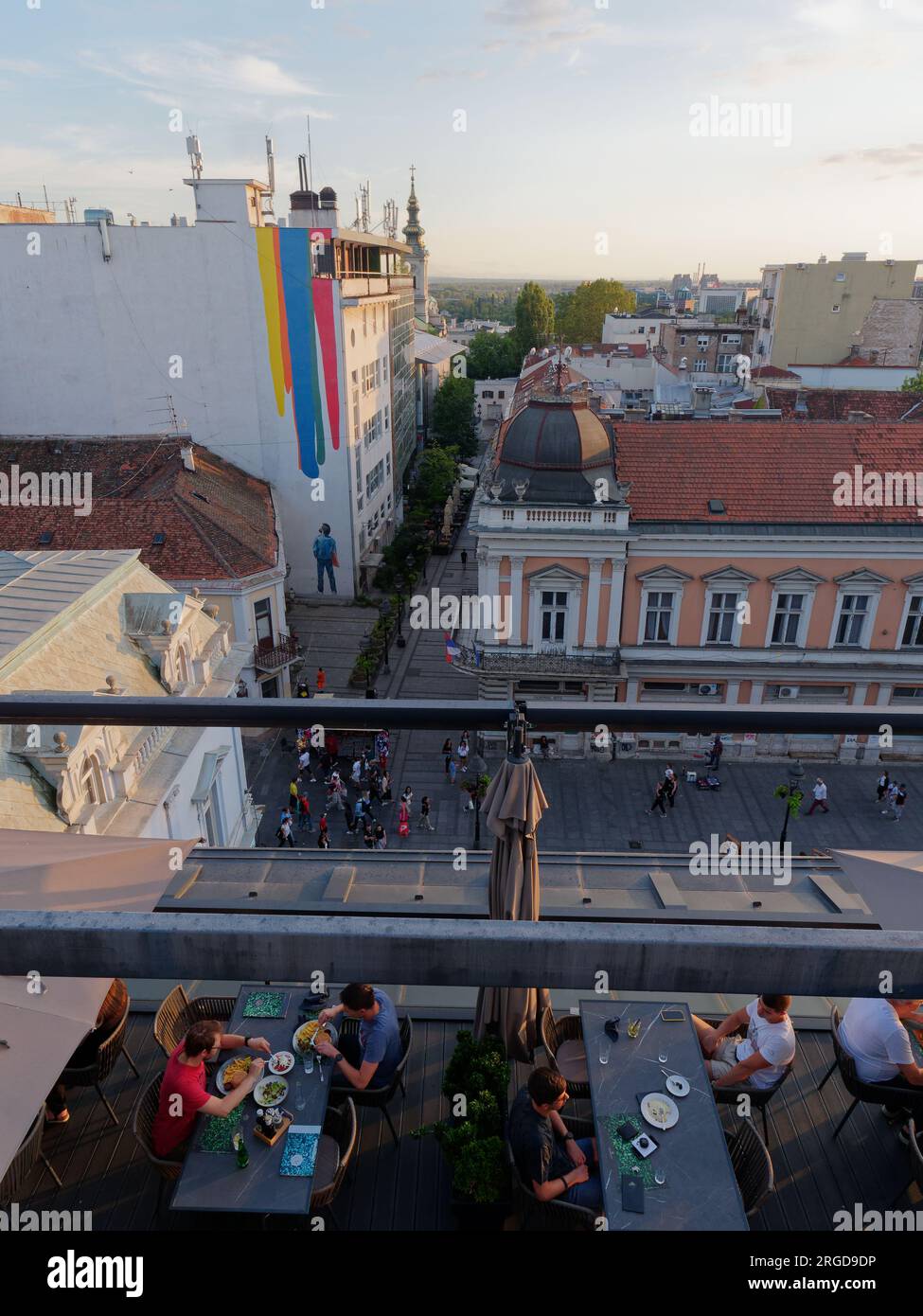 Vista elevata dal ristorante di una strada che include la Street art di un uomo in denim e strisce di colori sopra Belgrado, Serbia. Agosto 8,2023. Foto Stock