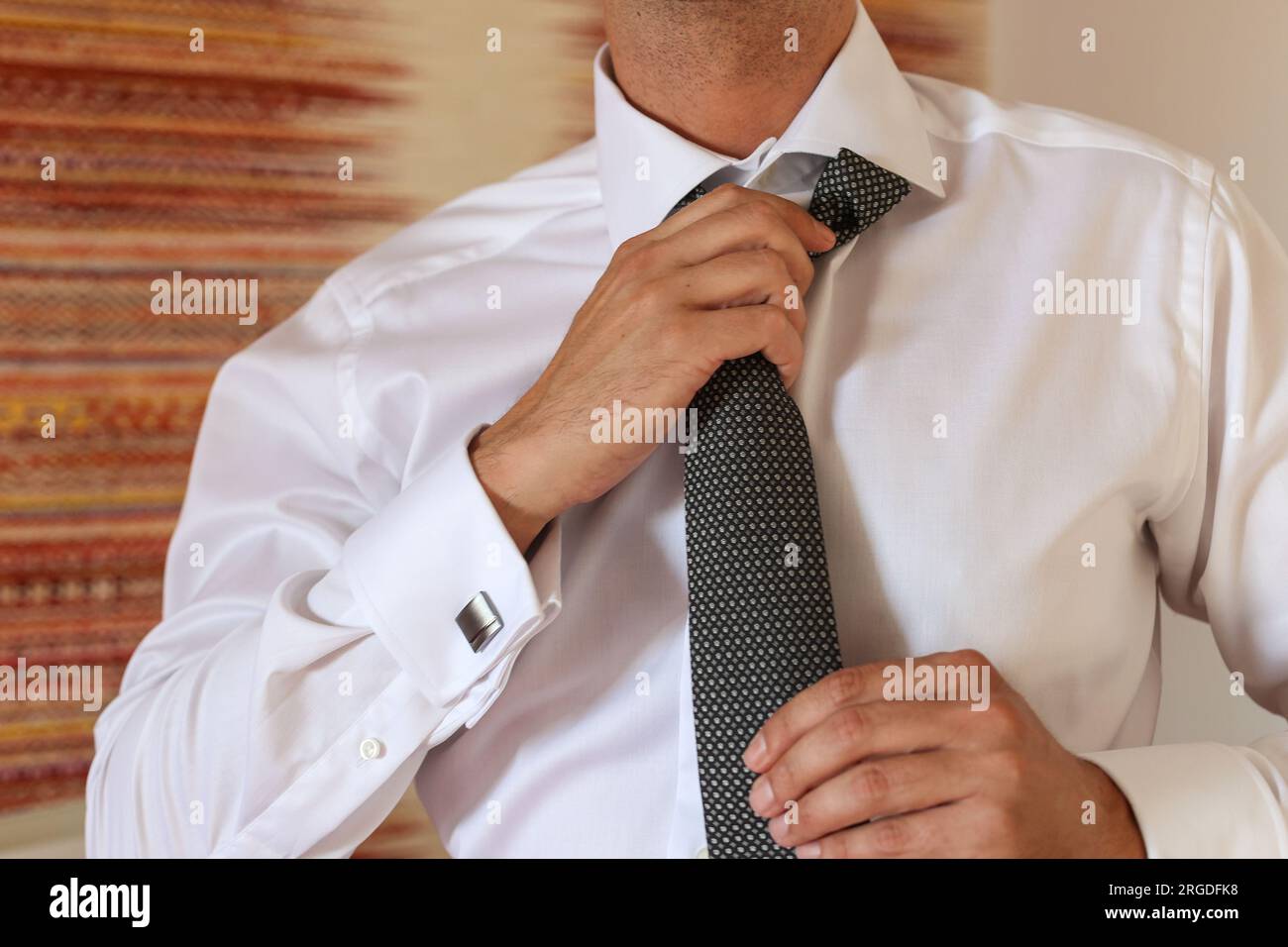 sposo che si mette la cravatta il giorno del suo matrimonio Foto Stock