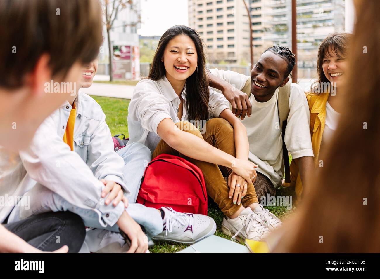 Amici multietnici degli studenti delle scuole superiori seduti all'aperto nel parco del campus. Foto Stock