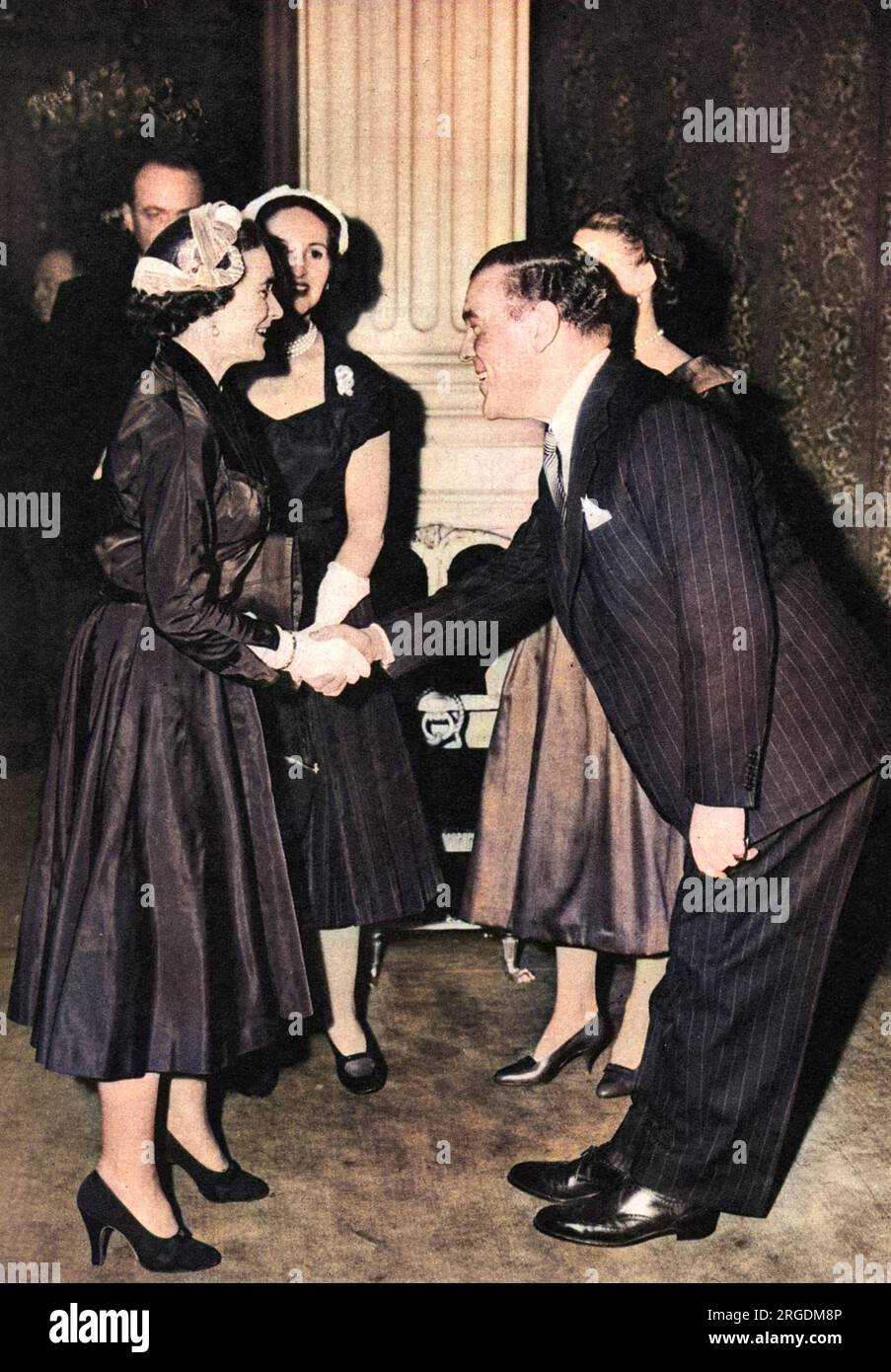 Sir Norman Bishop Hartnell (1901-1979) couturier britannico e design di moda preferito della Regina e della Regina madre, visto salutare un altro mecenate reale, la Principessa Alice, Duchessa di Gloucester (1901-2004), il cui abito da sposa ha progettato, ad un ricevimento di acquirenti di moda dall'estero tenutosi alla Mansion House nella City di Londra nel 1955. L'accoglienza è stata data da Lady Pamela Berry (ex Lady Pamela Smith) e ha visto la partecipazione dei principali designer di Londra, dei compratori d'oltremare, dei rappresentanti della stampa e del presidente del Board of Trade, Peter Thorneycroft e sua moglie. Foto Stock