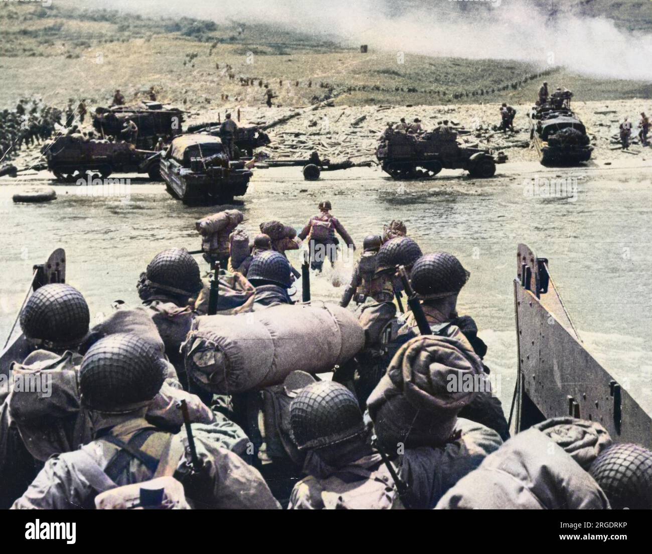 Le truppe d'assalto americane si preparano a sbarcare il loro mezzo di sbarco mentre si avvicina alla testa della spiaggia, Omaha Beach. Il fumo visibile sullo sfondo attesta il massiccio assalto di artiglieria navale, a sostegno dello sbarco. Serpenti di truppe si dirigono verso la spiaggia. Il D-Day iniziò il 6 giugno 1944 alle 6:30 e fu condotto in due fasi d'assalto û allo sbarco aereo delle truppe alleate seguito da un assalto anfibio della fanteria. Gli sbarchi in Normandia furono le più grandi azioni anfibie di un solo giorno mai intraprese, coinvolgendo circa 400.000 militari e personale navale. Foto Stock