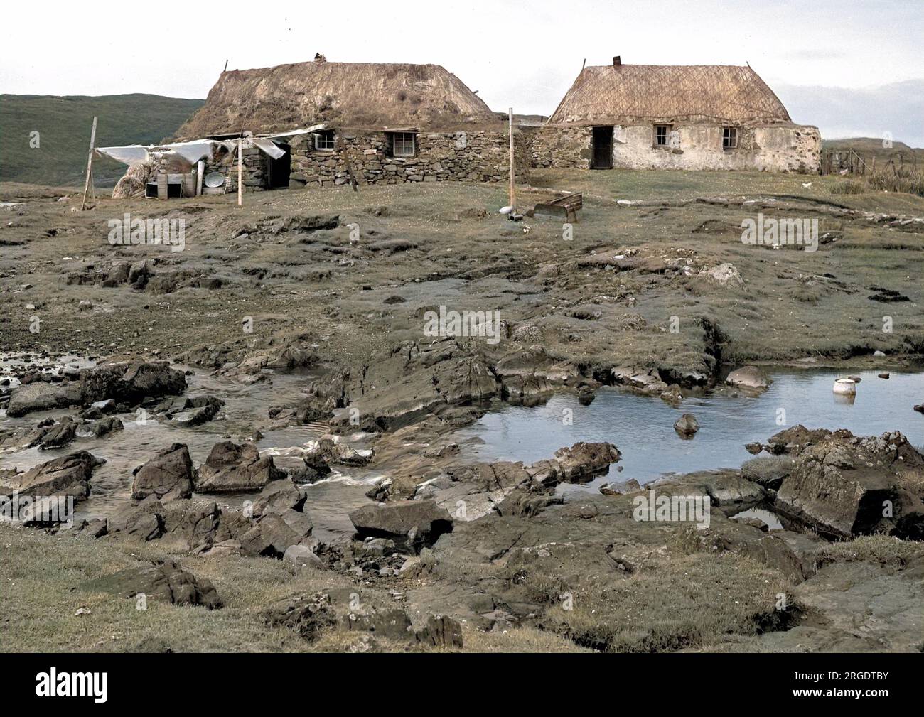 Due cottage rustici in un paesaggio desolante, con lavaggio flapping su una linea di vestiti, a Timsgarry, Uig, Isola di Lewis, Ebridi esterne, Scozia. Foto Stock