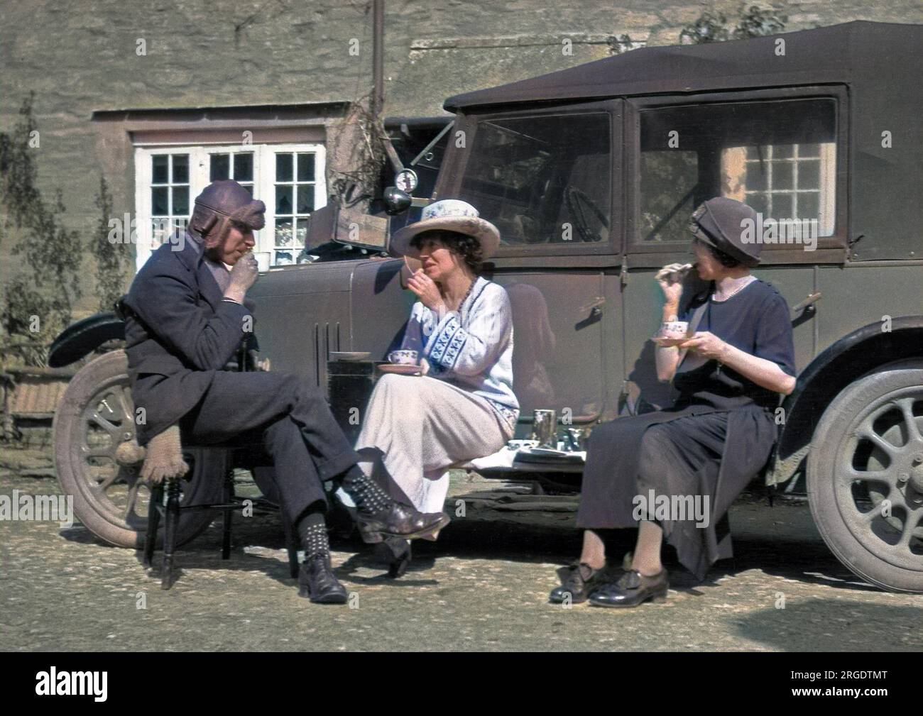 Tre persone picnicking con tazze di porcellana sul lato di una macchina. Foto Stock