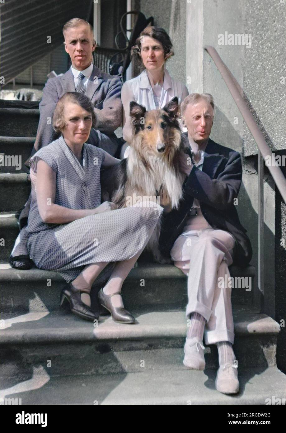 Quattro persone (due uomini e due donne) seduti sui gradini con un cane collie. Foto Stock