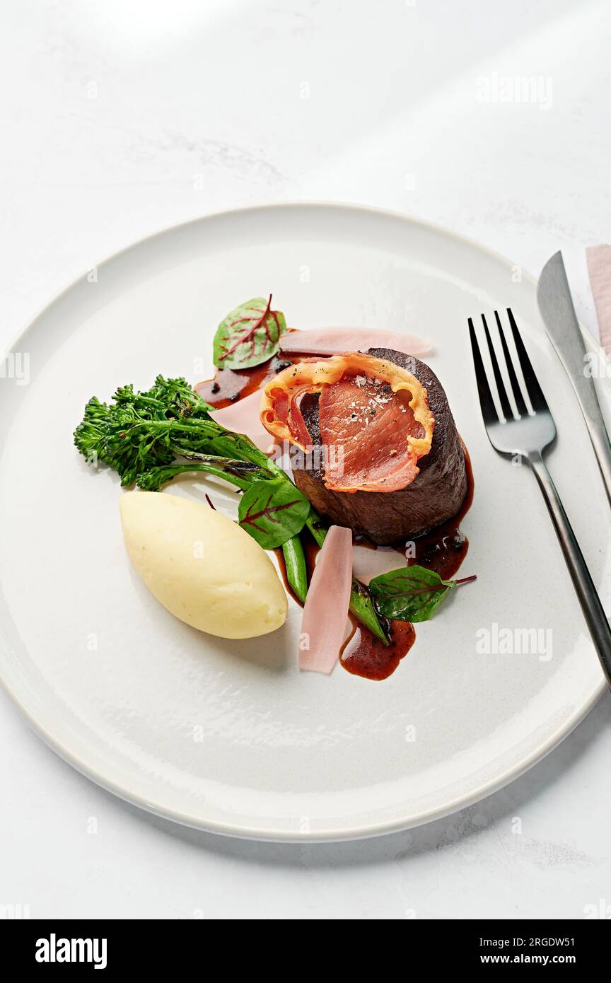 Filetto d'occhio, purè di patate, broccolini carbonizzati, jus di tartufo nero, petali di scalogno sottaceto, pancetta croccante Foto Stock