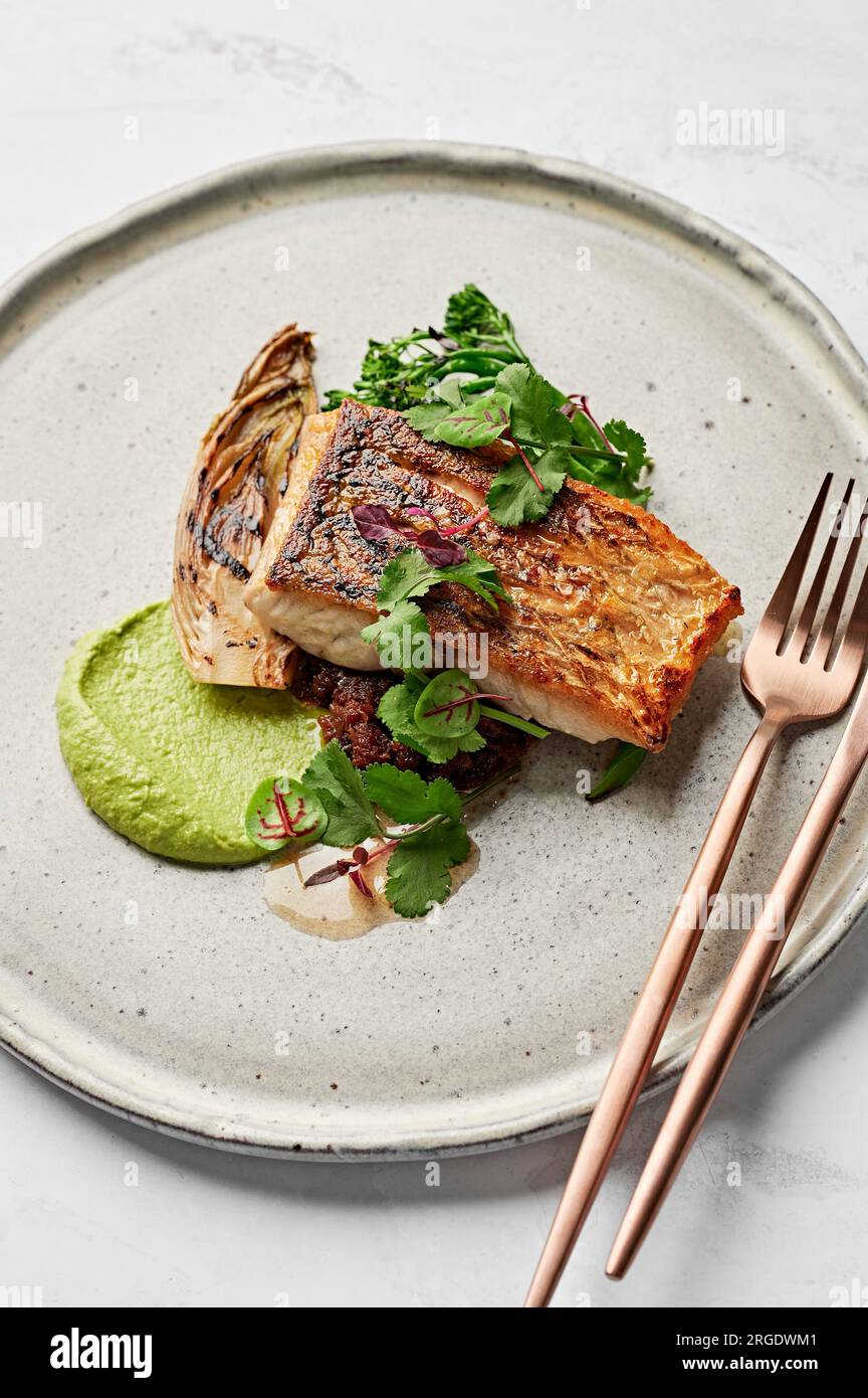 Pesce Barramundi, purea di porri, salsa XO di pesce, strega brasata, broccolini carbonizzati Foto Stock