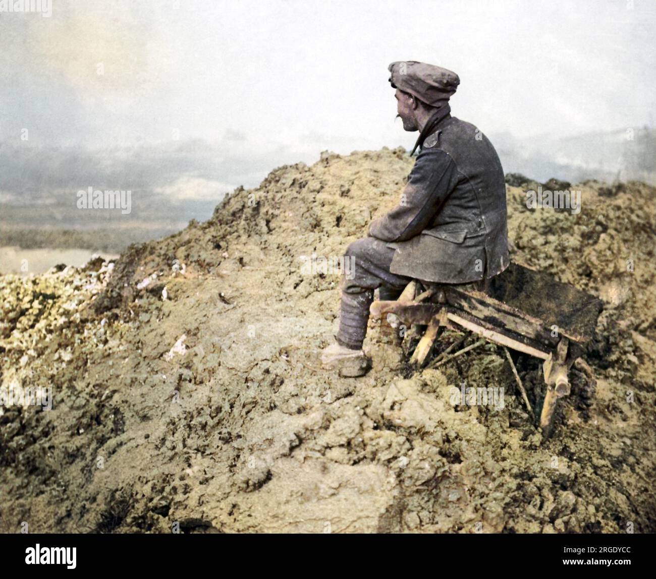 Un soldato britannico seduto su uno sgabello su una collina fangosa sul fronte occidentale durante la prima guerra mondiale, a guardare in lontananza. Foto Stock