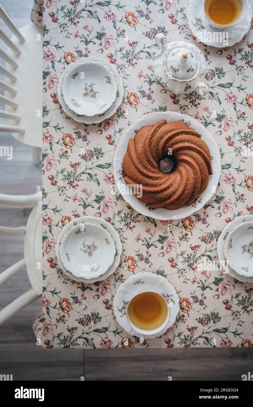 Una torta vegana su un tavolo floreale con tazze di tè Foto Stock