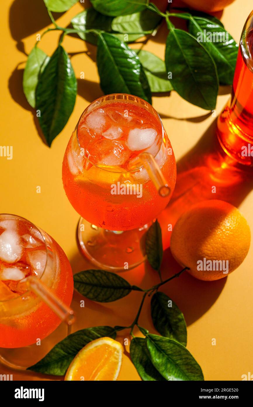 cocktail aperol spritz con ghiaccio, una bevanda rinfrescante appannata, su sfondo arancione, luce del sole, ombre, una bevanda estiva in un bicchiere di vino Foto Stock