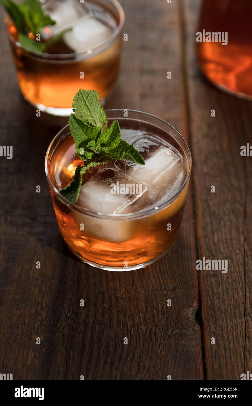 Tè freddo alla pesca in un bicchiere piccolo con cubetti di ghiaccio e foglie di menta fresca. Foto Stock