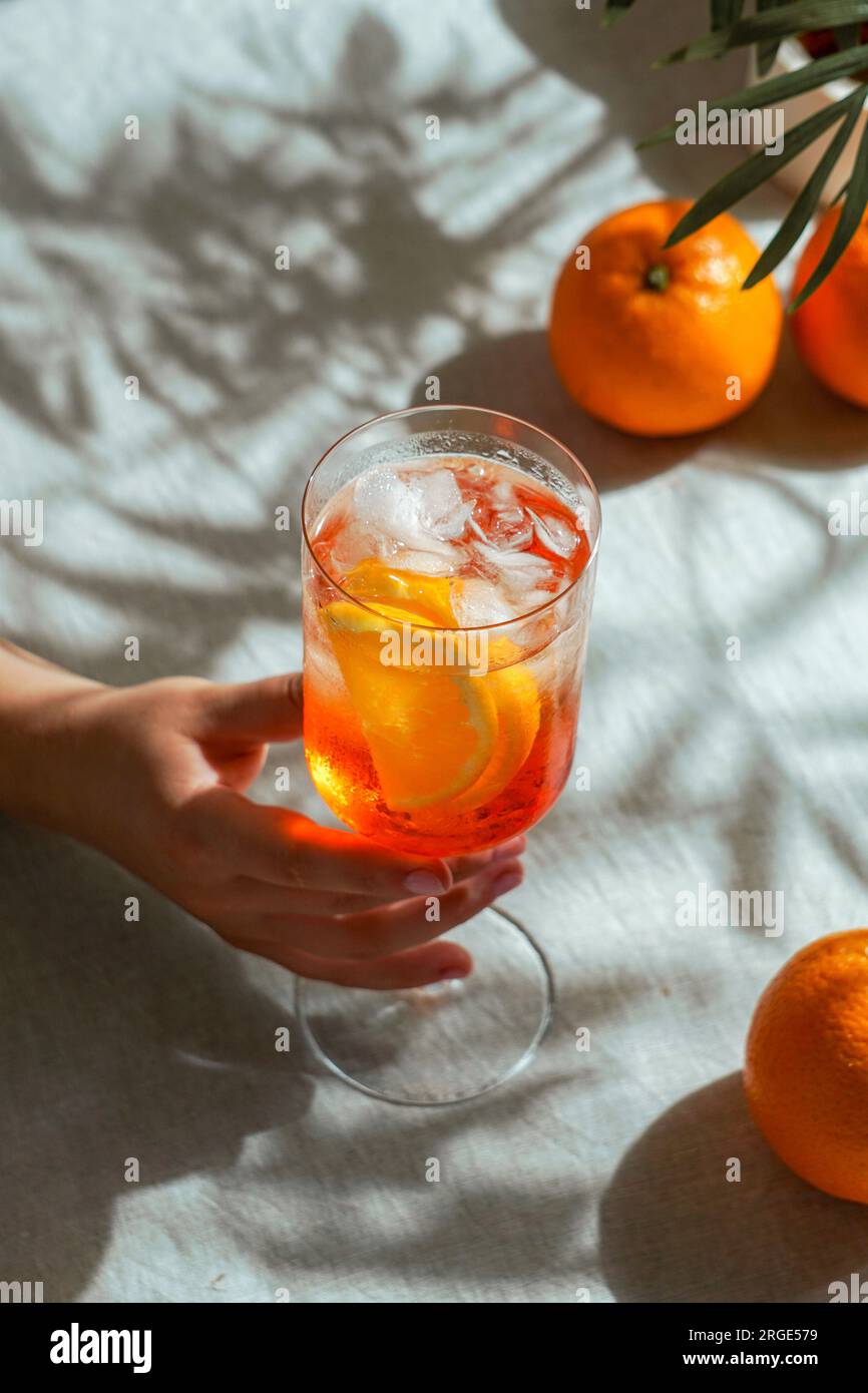 aperol spritz, cocktail, su una tovaglia di lino, ombre, luce solare intensa, drink estivo in bicchiere Foto Stock
