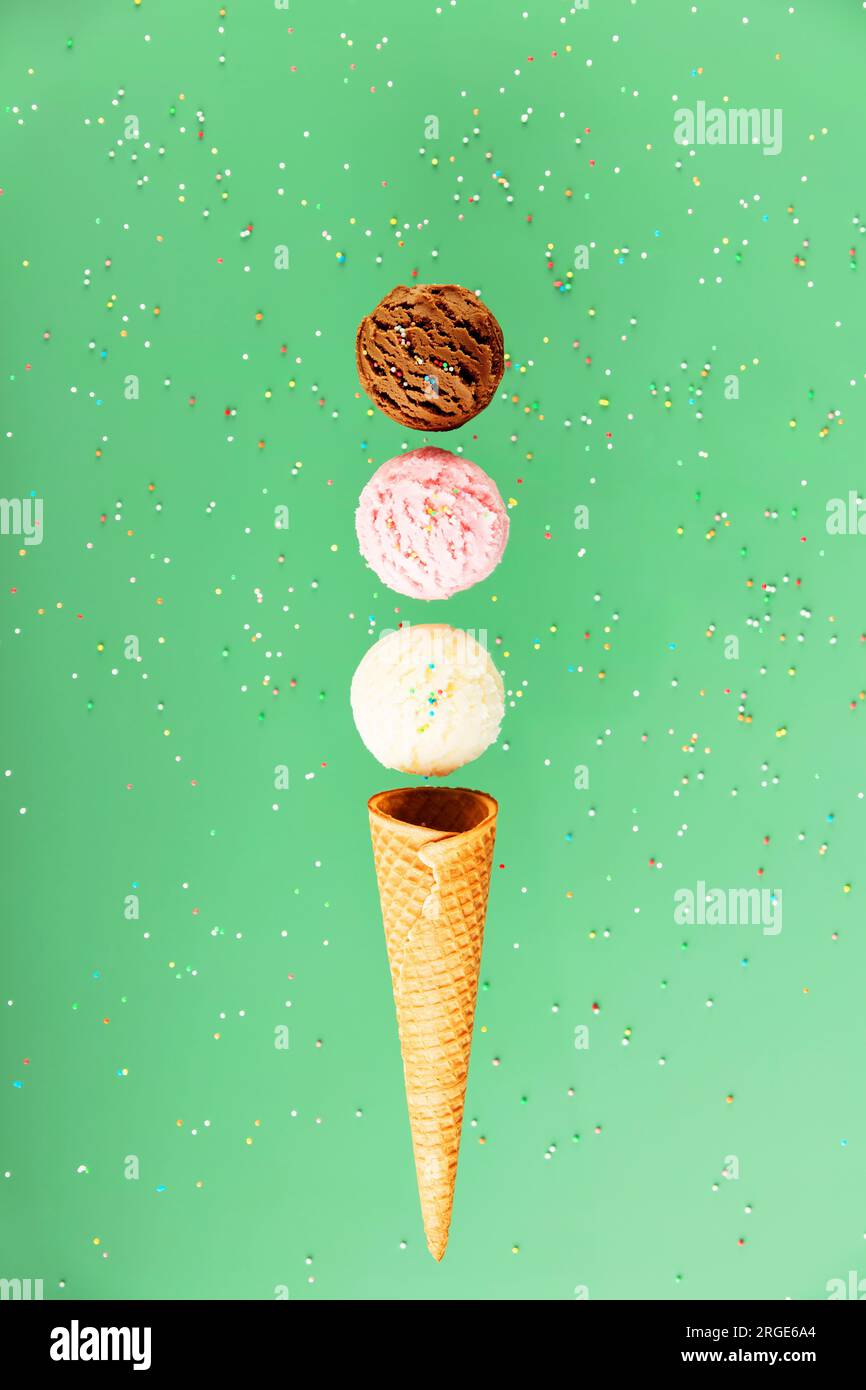 Cioccolato, vaniglia, sessole di fragole e cono cialde su sfondo verde con spruzzi colorati, concetto levitante. Atmosfera primaverile o estiva Foto Stock