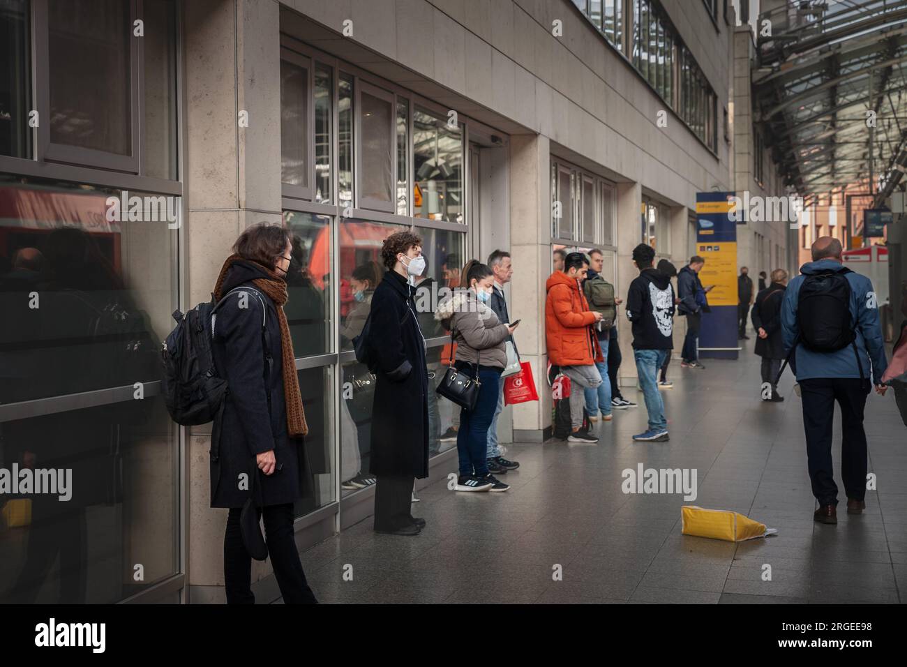 Foto di uomini e donne in attesa di un treno sui binari della stazione ferroviaria hauptbahnhof di Koln, indossando maschere facciali durante il Coronavirus Covid 19 ore Foto Stock
