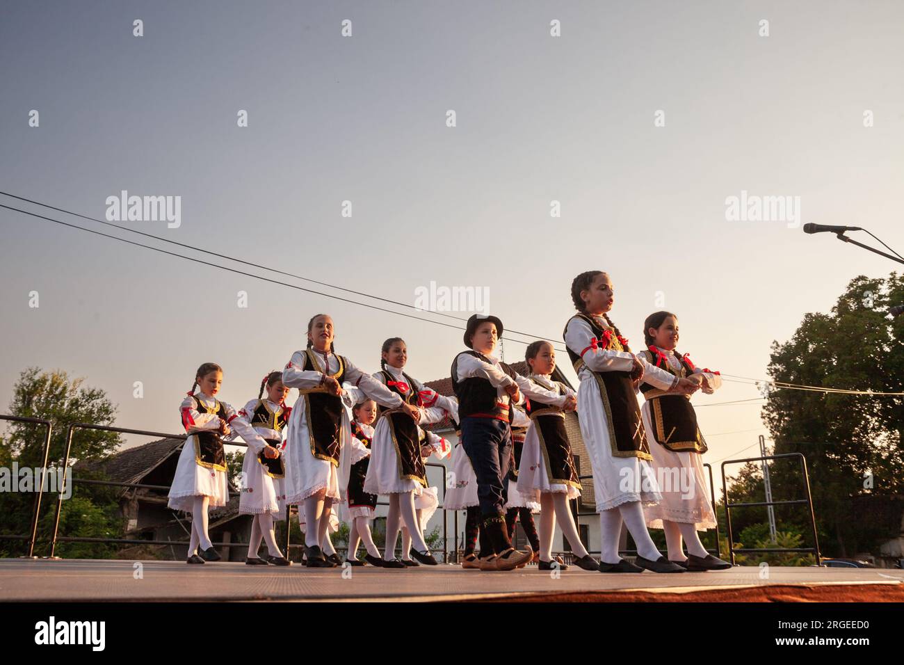 Foto di un gruppo di bambini, bambini, persone che ballano un kolo serbo nel villaggio di Pecinci, Serbia. Kolo è una danza circolare slava del sud, trovata unde Foto Stock