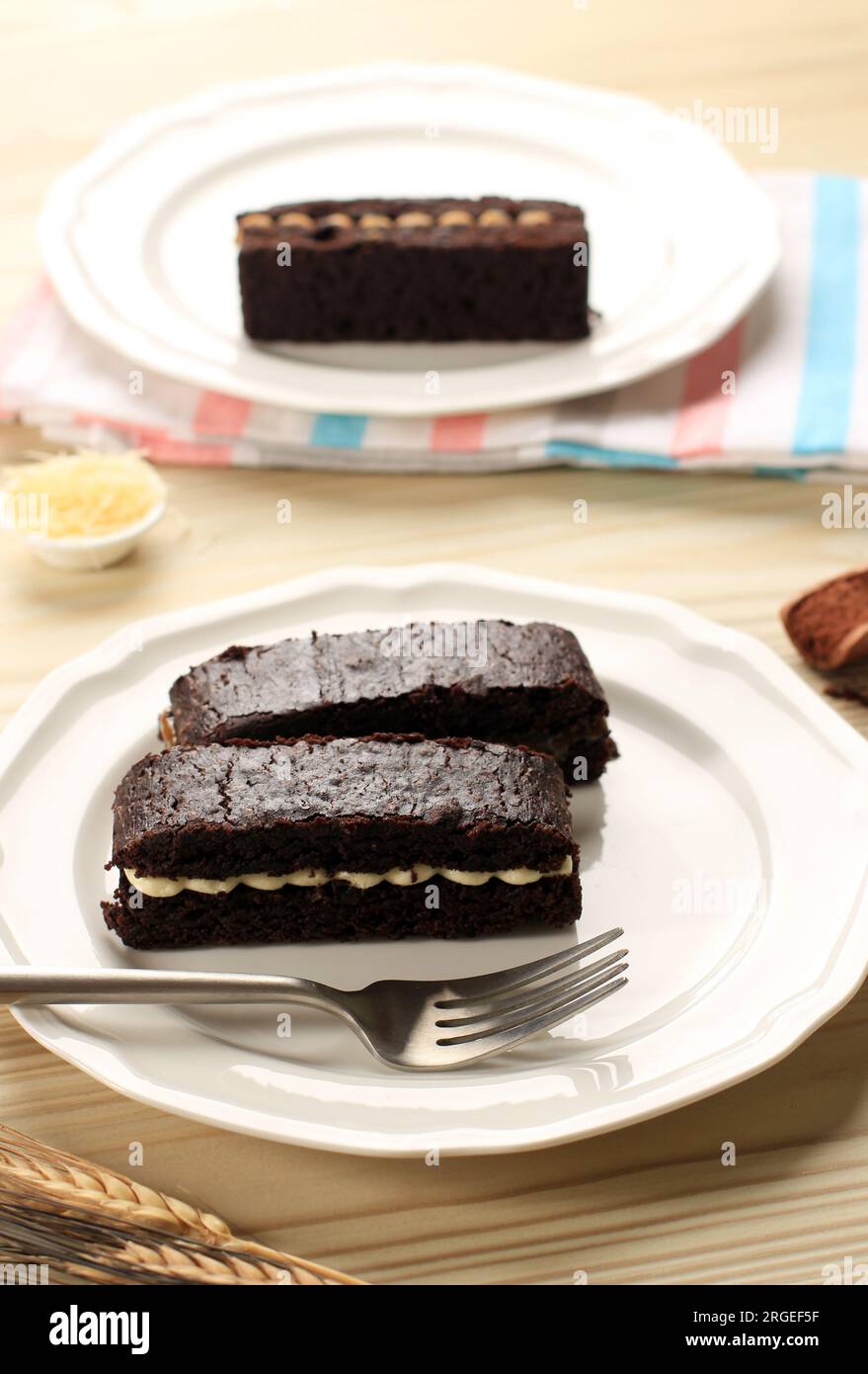Brownie di torta al cioccolato a fette con crema all'interno, su piatto bianco Foto Stock