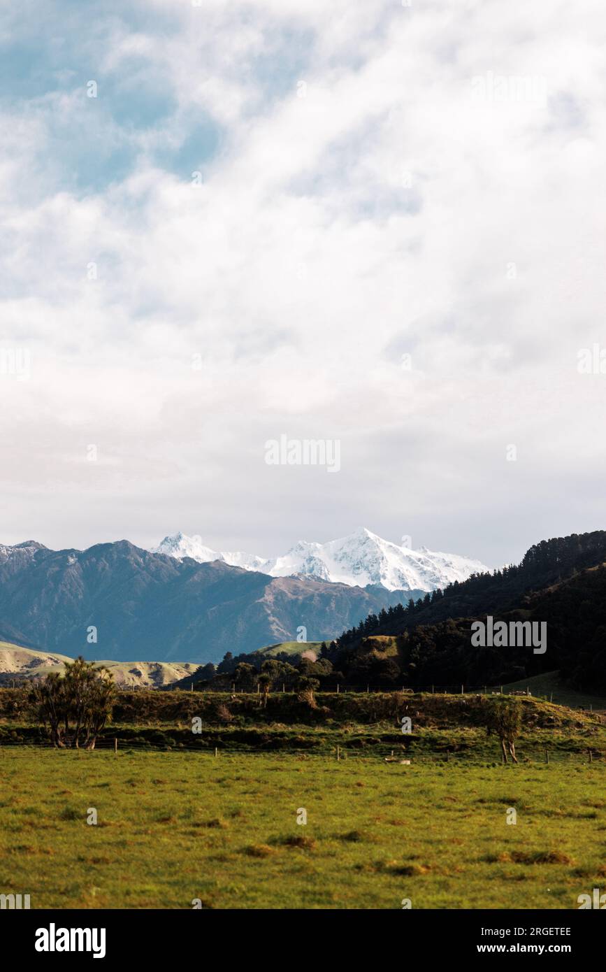 Un'immagine di montagne innevate che si affacciano sui terreni agricoli Foto Stock