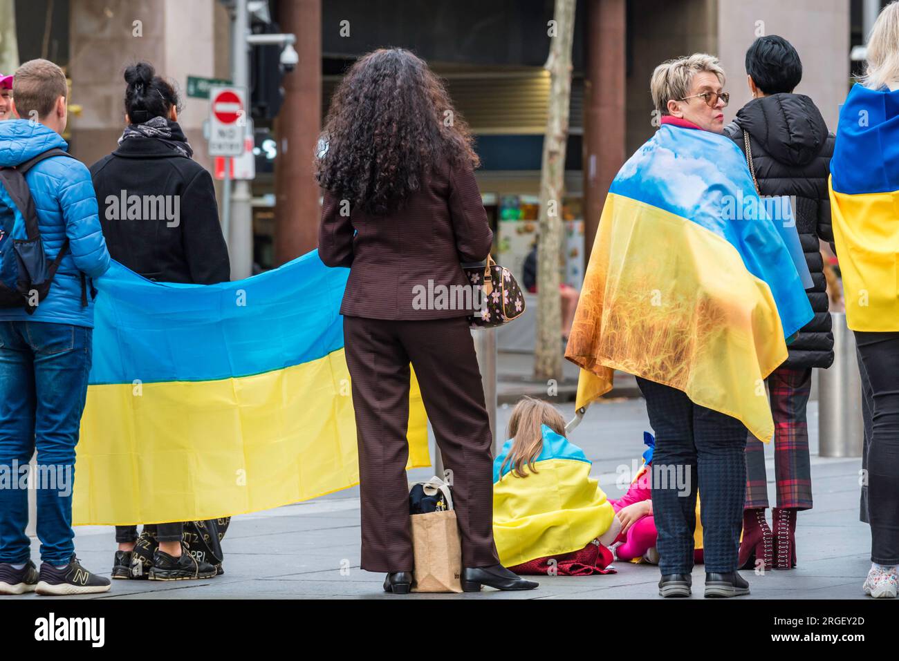 I manifestanti a un raduno pro-Ucraina a Sydney, in Australia, si alzano con i colori nazionali blu e giallo e le bandiere ucraine Foto Stock