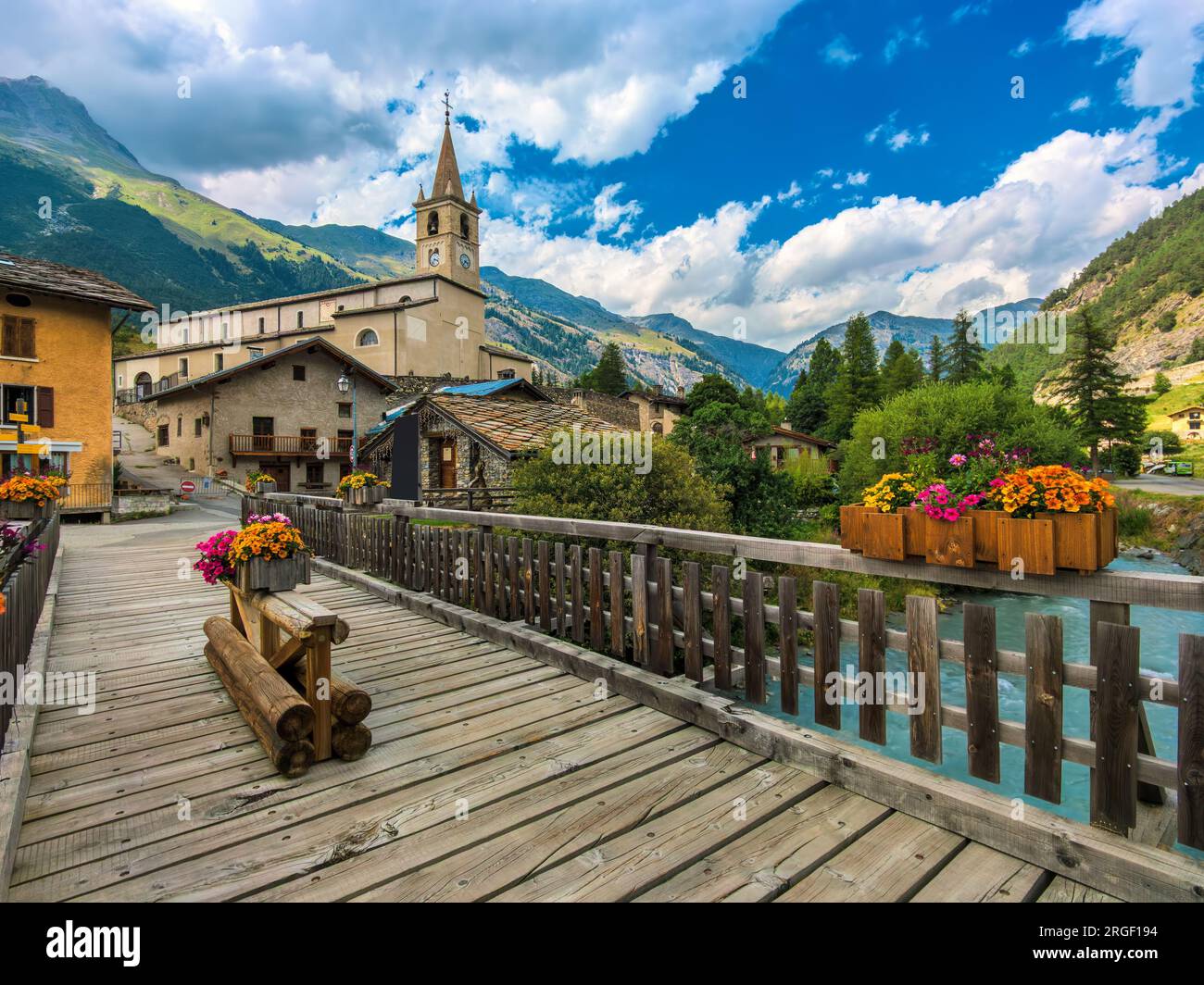 Vista del ponte di legno sul fiume alpino come chiesa e case sullo sfondo in piccolo circondato dalla città montana della Val-Cenis, in Francia. Foto Stock