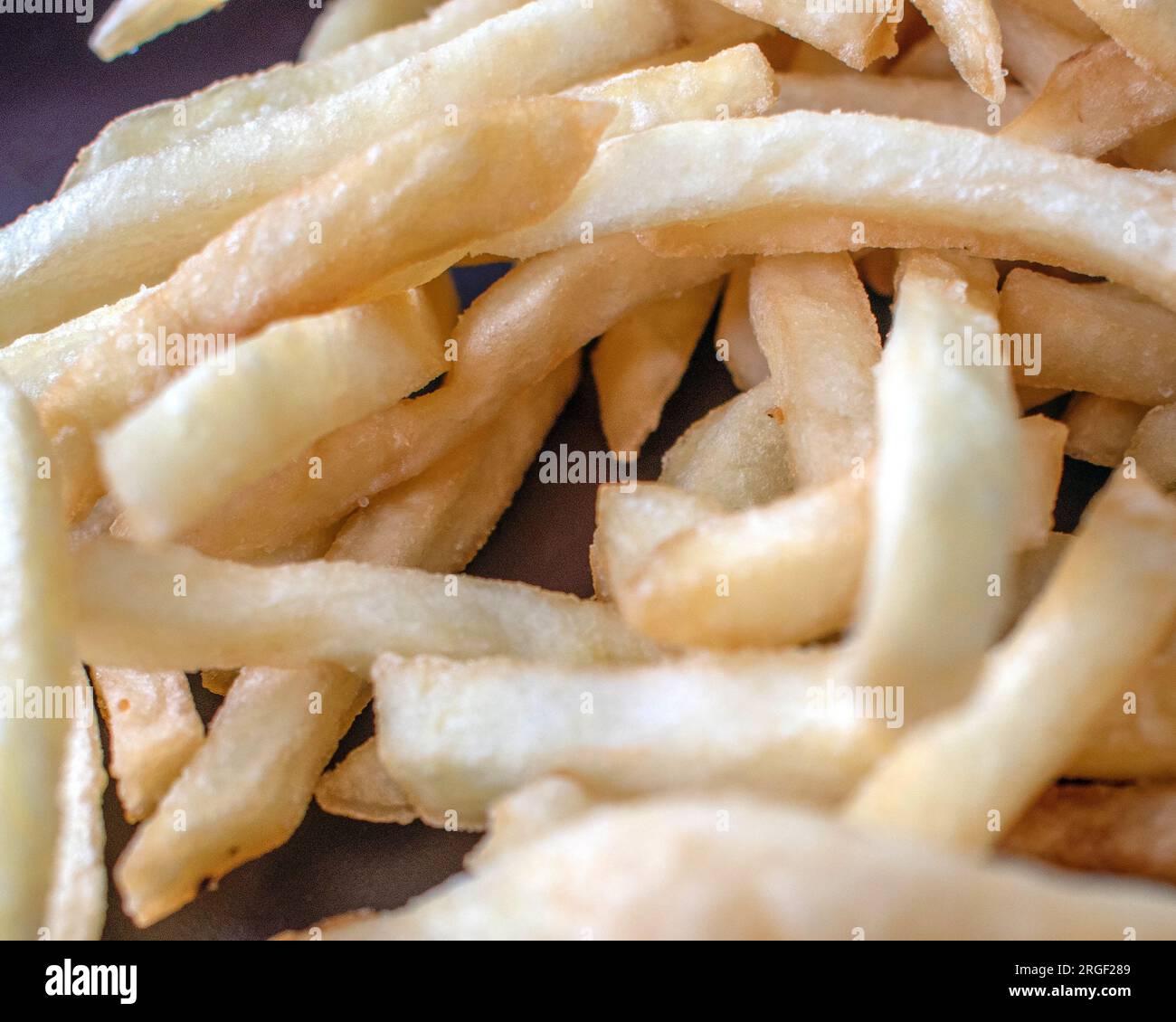 Patatine fritte: Fotografia ravvicinata che mostra patatine fritte fresche e perfettamente dorate su uno sfondo scuro. L'attenzione è posta in modo esperto Foto Stock