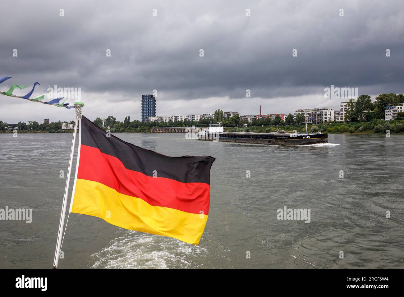 Nave da carico sul Reno, riva del Reno nel distretto di Muelheim, bandiera tedesca su una barca da escursione, Colonia, Germania. Frachtschiff auf dem Rhein, R. Foto Stock