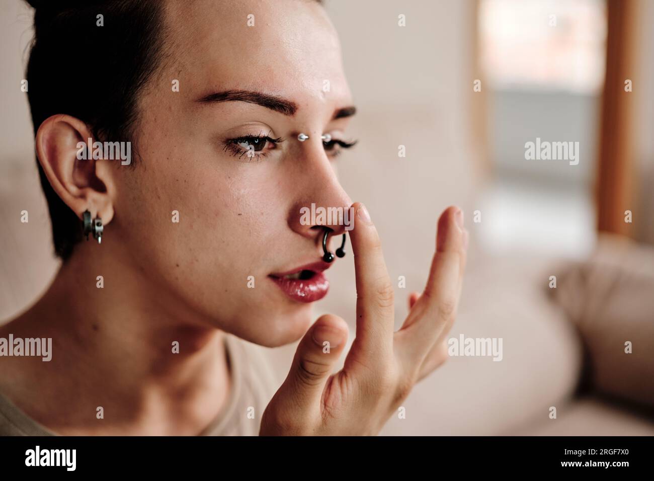 Un uomo gay con piercing che si fa a casa Foto Stock