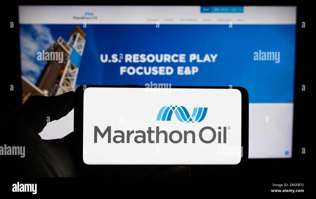 Persona che possiede un telefono cellulare con il logo della società petrolifera statunitense Marathon Oil Corporation sullo schermo davanti alla pagina Web. Concentrarsi sul display del telefono. Foto Stock