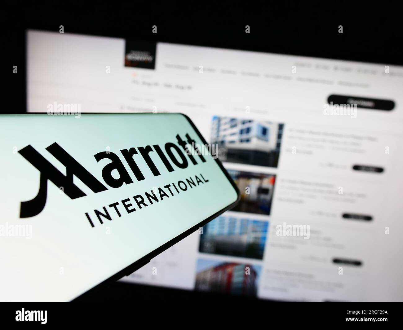 Telefono cellulare con logo della società alberghiera statunitense Marriott International Inc. Sullo schermo davanti al sito Web. Mettere a fuoco il display centrale sinistro del telefono. Foto Stock