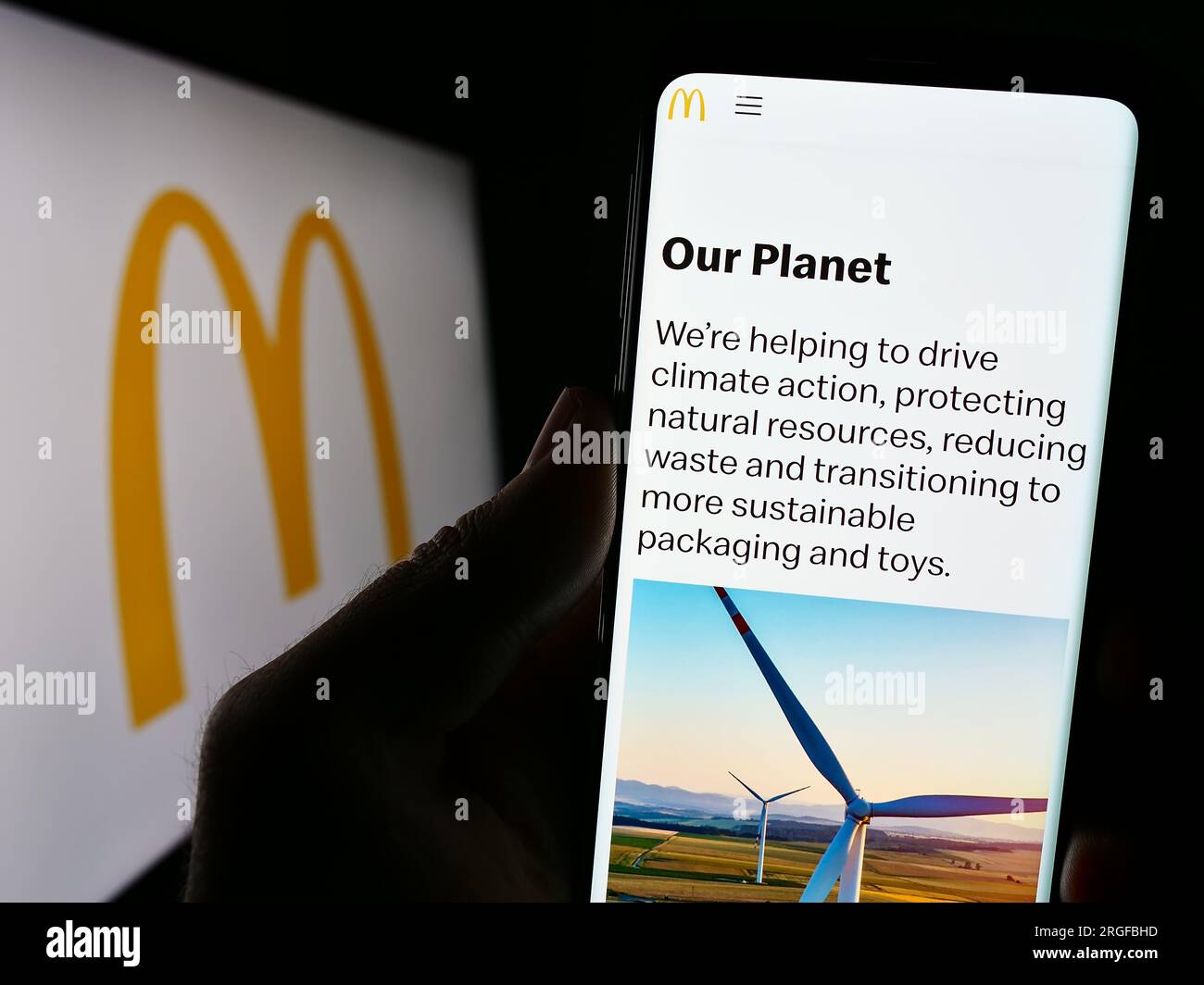 Persona che tiene il cellulare con il sito Web dell'azienda statunitense di fast food McDonald's Corporation sullo schermo davanti al logo. Concentrarsi sul centro del display del telefono. Foto Stock