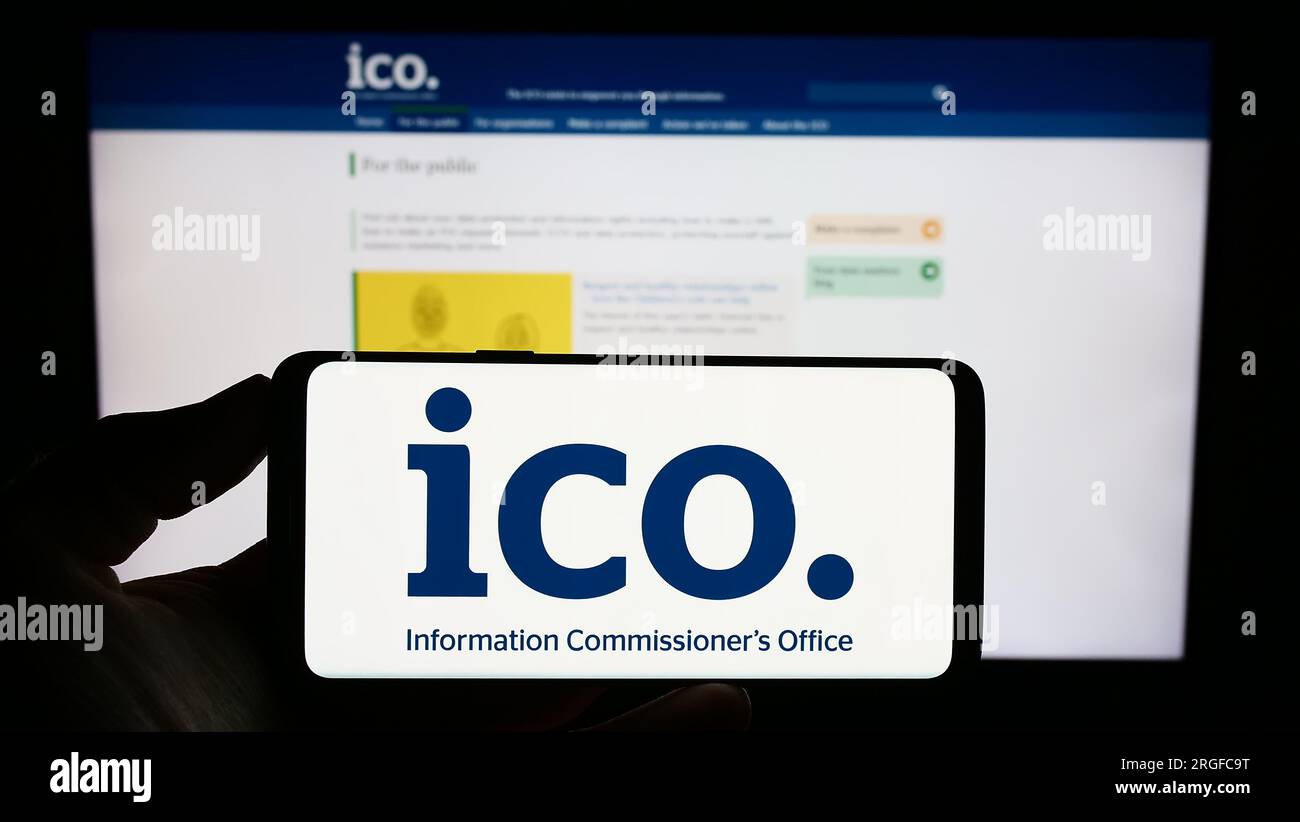 Persona in possesso di un cellulare con il logo del British Information Commissioner's Office (ICO) sullo schermo davanti alla pagina web. Concentrarsi sul display del telefono. Foto Stock