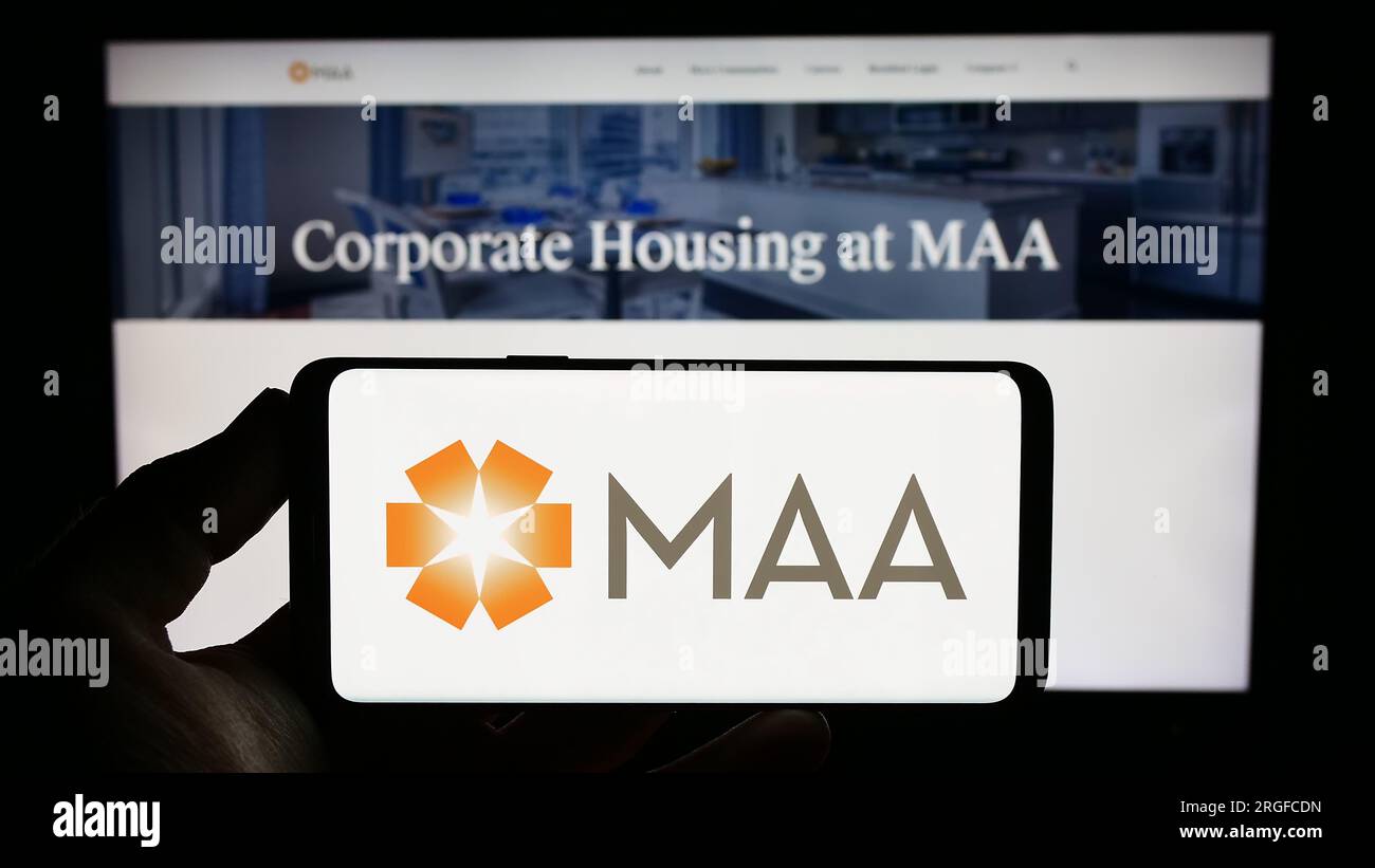 Persona che possiede un telefono cellulare con il logo di Mid-America Apartment Communities Inc (MAA) sullo schermo davanti alla pagina Web. Concentrarsi sul display del telefono. Foto Stock