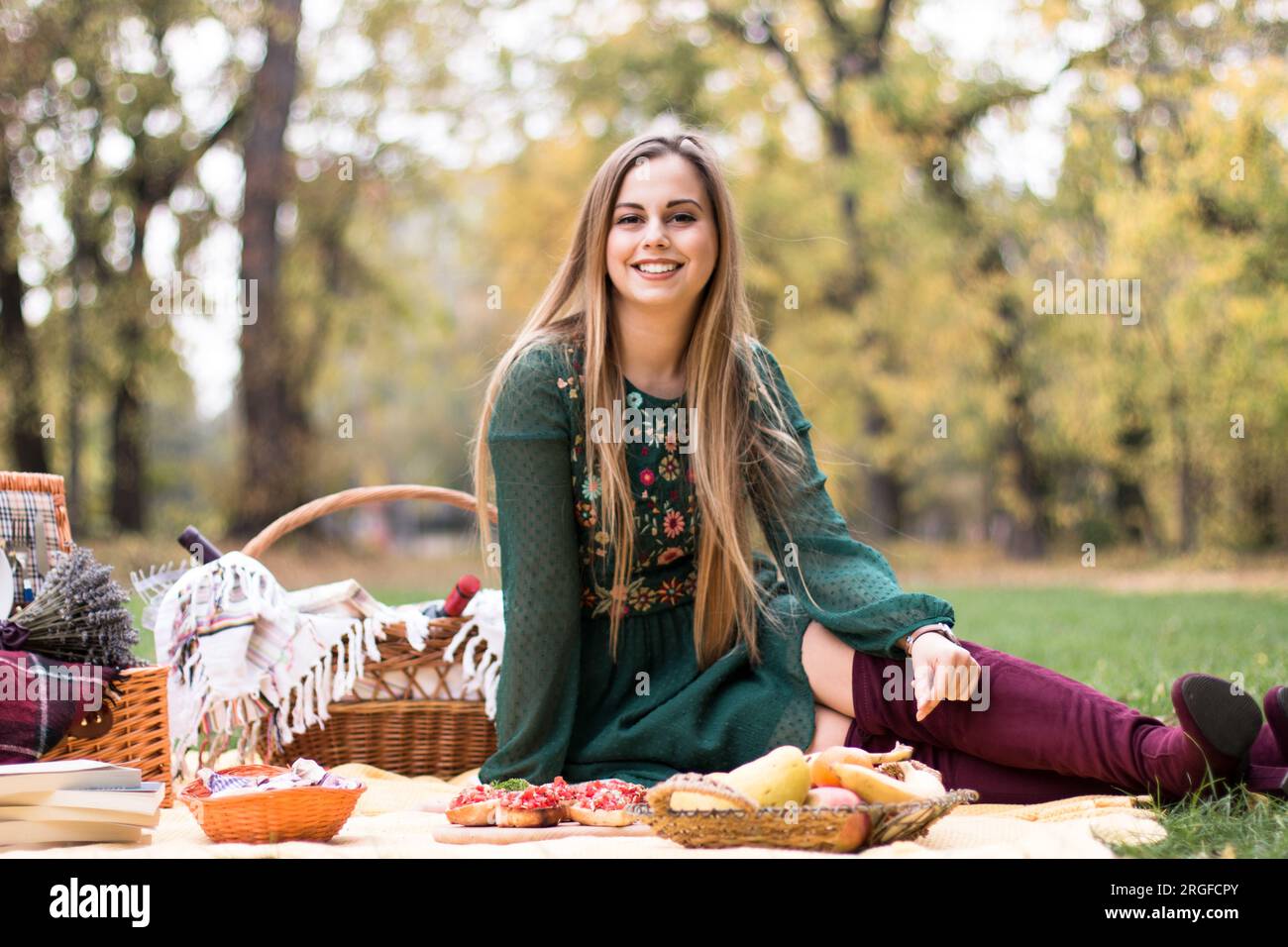 Bella donna bionda in un picnic nel parco, in attesa che arrivino i suoi amici. Foto Stock