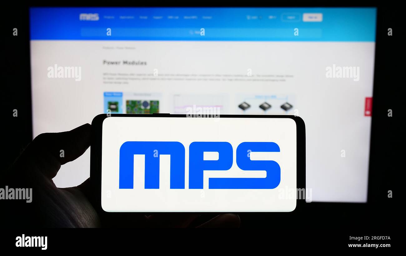 Persona che tiene il cellulare con il logo della società americana Monolithic Power Systems Inc (MPS) sullo schermo davanti alla pagina Web. Concentrarsi sul display del telefono. Foto Stock