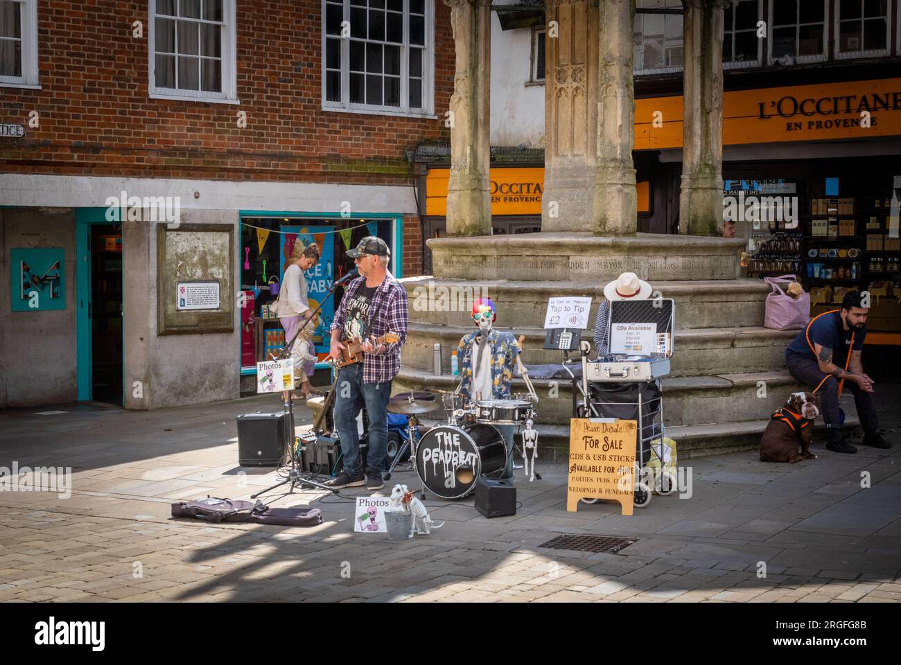 Un musicista blues si esibisce con uno scheletro meccanico di fronte alla City Cross, o Butter Cross, nell'antica città di Winchester, H Foto Stock