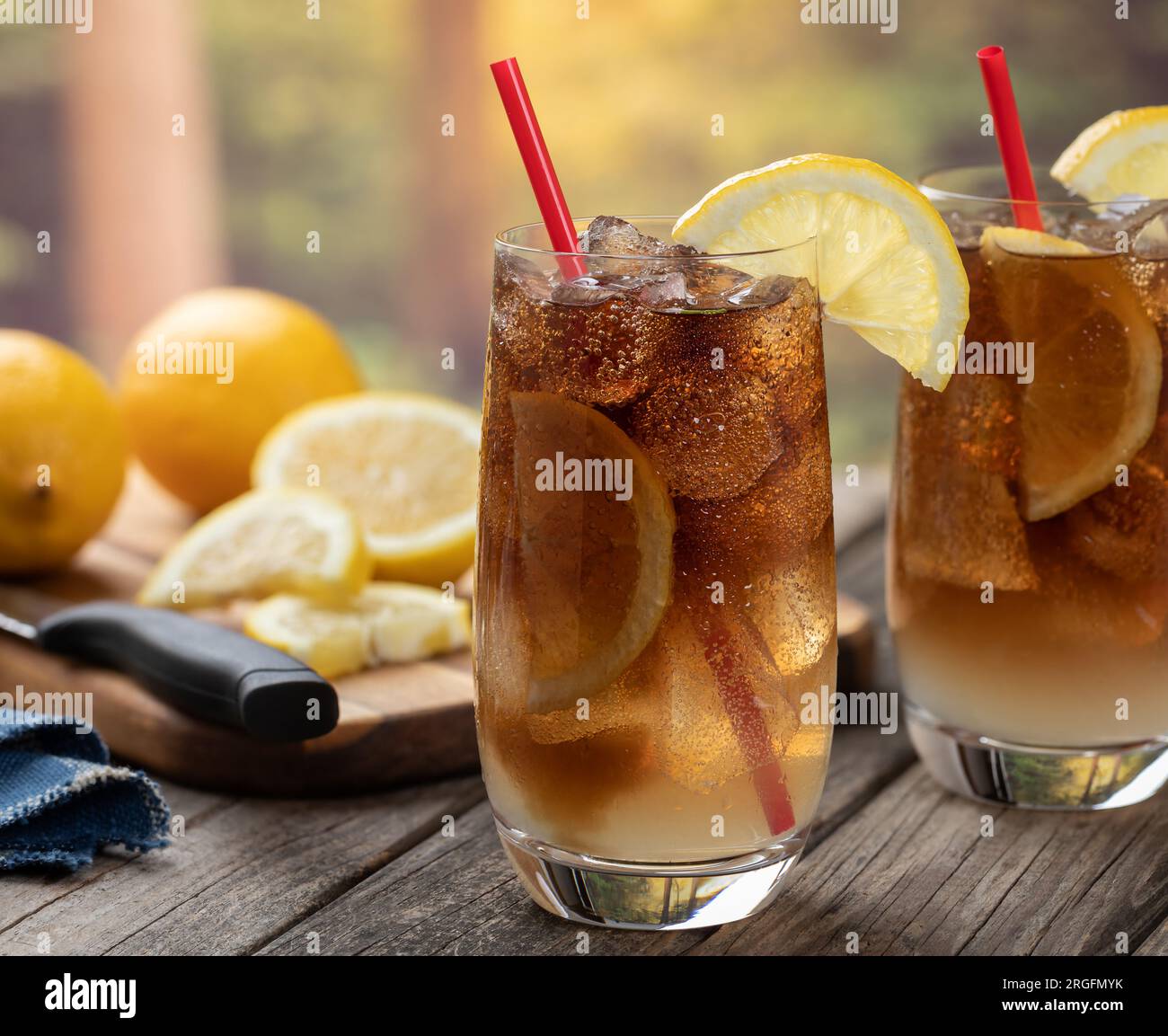 Cocktail con tè freddo lungo dell'isola con fette di limone all'aperto su un tavolo rustico in legno e sfondo naturale Foto Stock