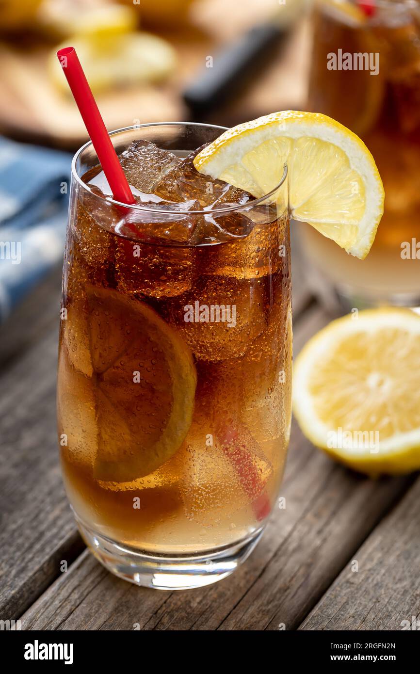 Cocktail con tè freddo lungo dell'isola con fette di limone all'aperto su un tavolo rustico in legno Foto Stock