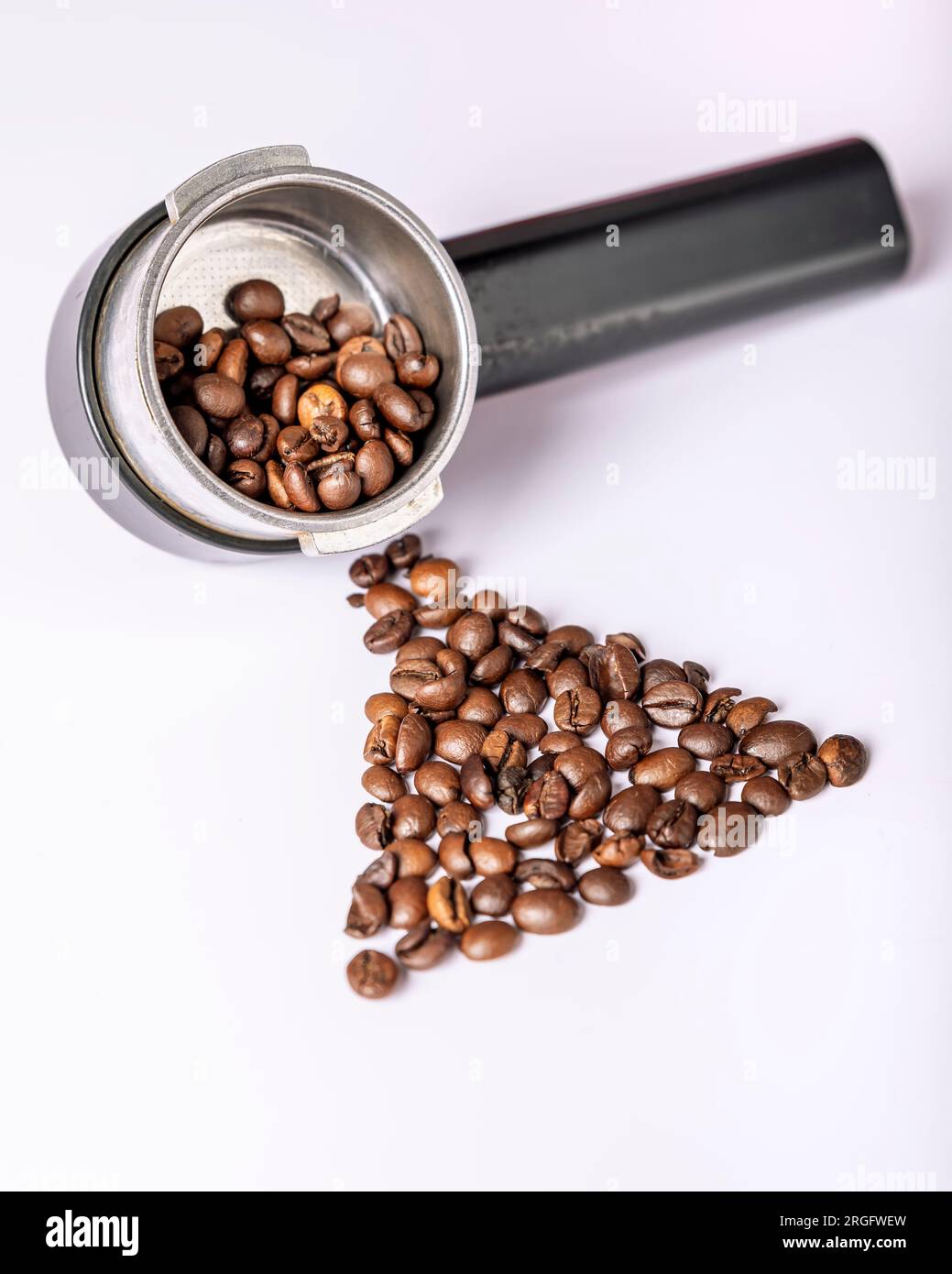 I chicchi di caffè sono in un braccio per la macchina da caffè e su un tavolo bianco Foto Stock