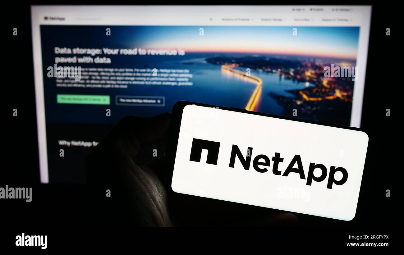 Persona che possiede uno smartphone con il logo della società cloud statunitense NetApp Inc. Sullo schermo di fronte al sito Web. Concentrarsi sul display del telefono. Foto Stock