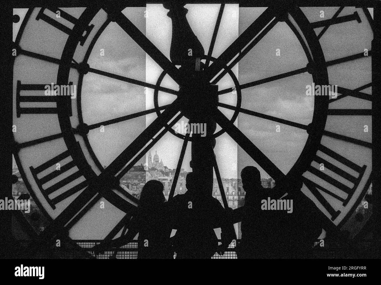Fotografia in bianco e nero dell'archivio degli anni '1990 di persone che si trovano all'interno dietro, e guardano attraverso, il volto dell'orologio esterno per la Gare d'Orsay, ora Museo d'Orsay, Parigi. Foto Stock